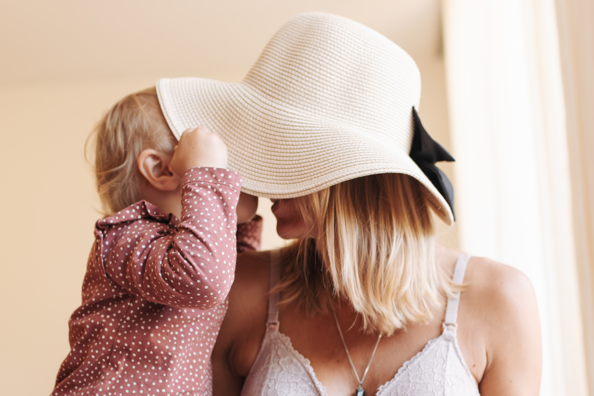 Werdende Mama mit Hut gibt ihrer älteren Tochter ein Küssen.