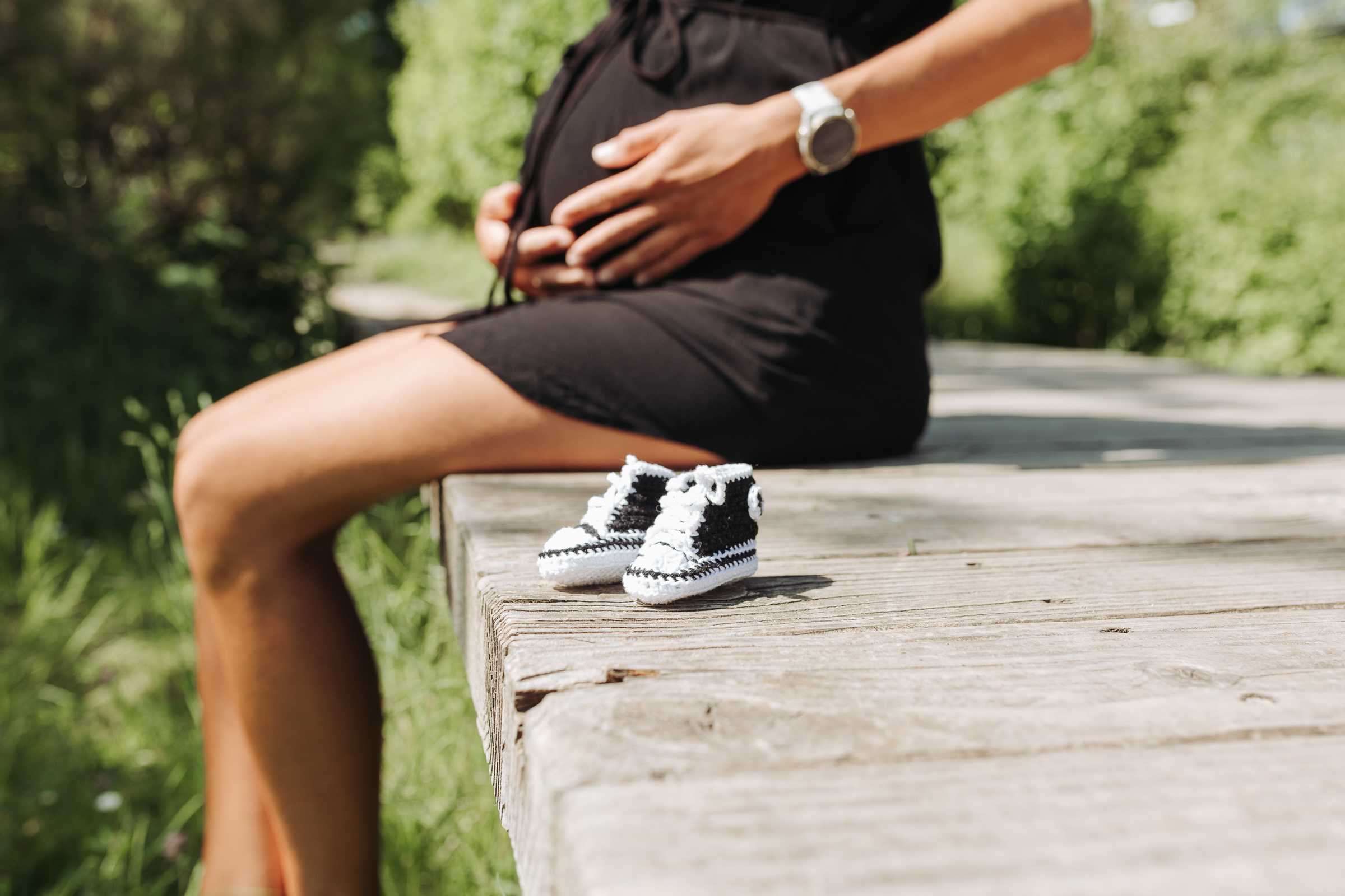 Ausschnitt eines Babybauches mit kleinen gehäkelten Babyschuhen