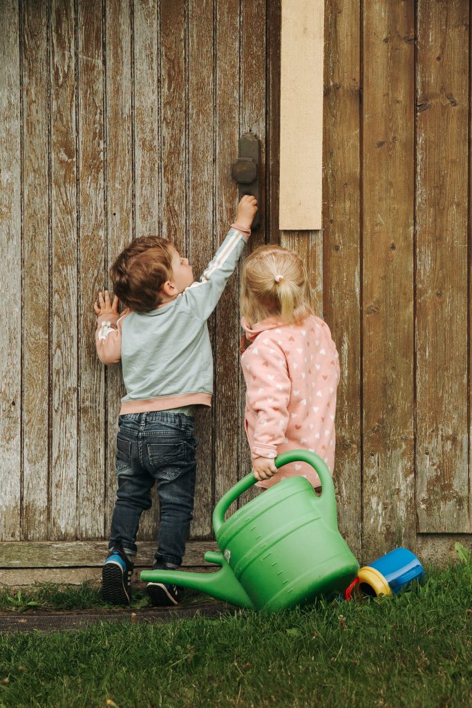 Ein kleiner Junge und ein kleines Mädchen versuchen eine Tür aufzumachen.