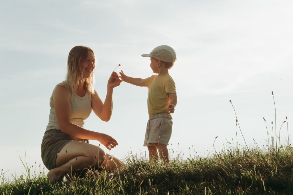 Ein kleiner Junge überreicht seiner Mama eine Blume.