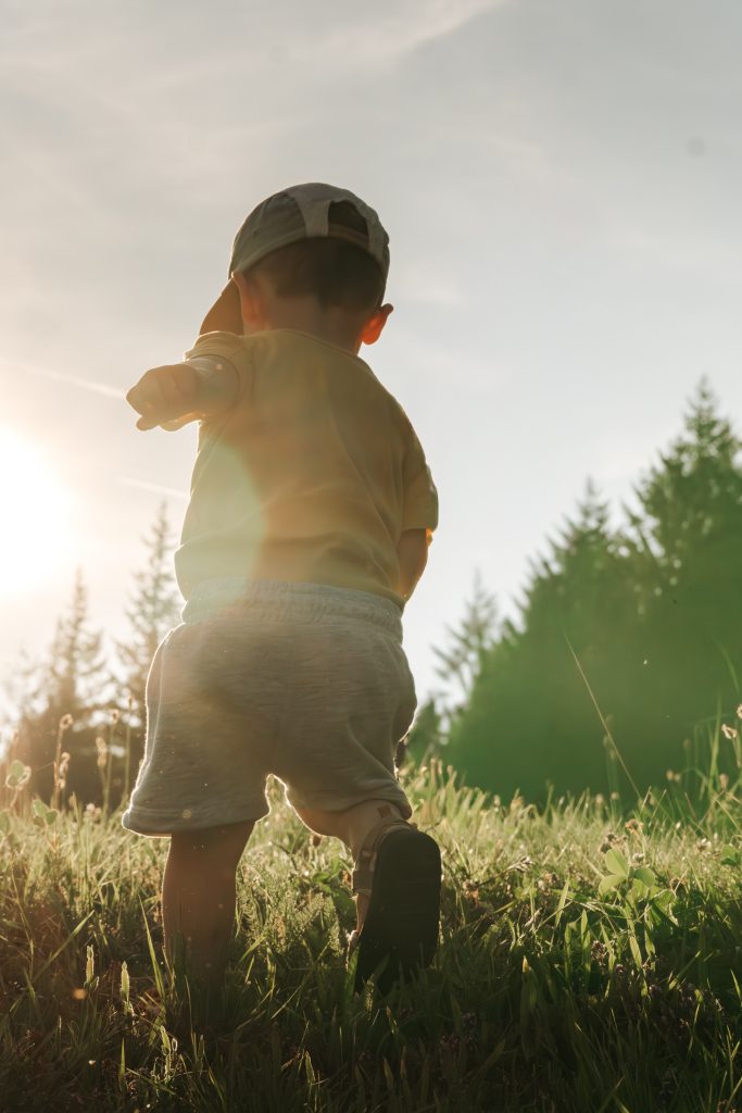kleiner Junge rennt auf einer Wiese im Schwarzwald der Sonne entgegen.