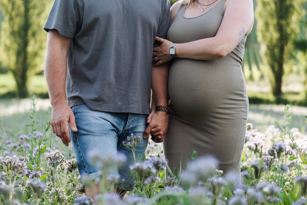 Schwangere Frau mit Partner im Blumenfeld